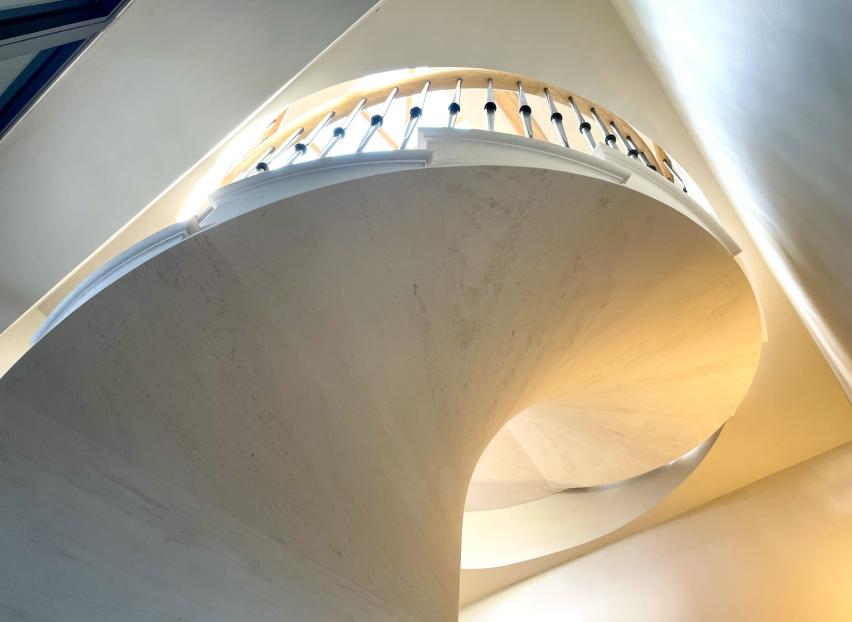 Sculptural stone soffit beneath a freestanding spiral staircase by Carvero.