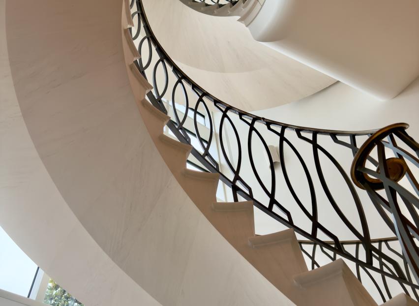Close-up of the hand-carved underside of a helical limestone staircase tracking the elegant twist of the stone structure.